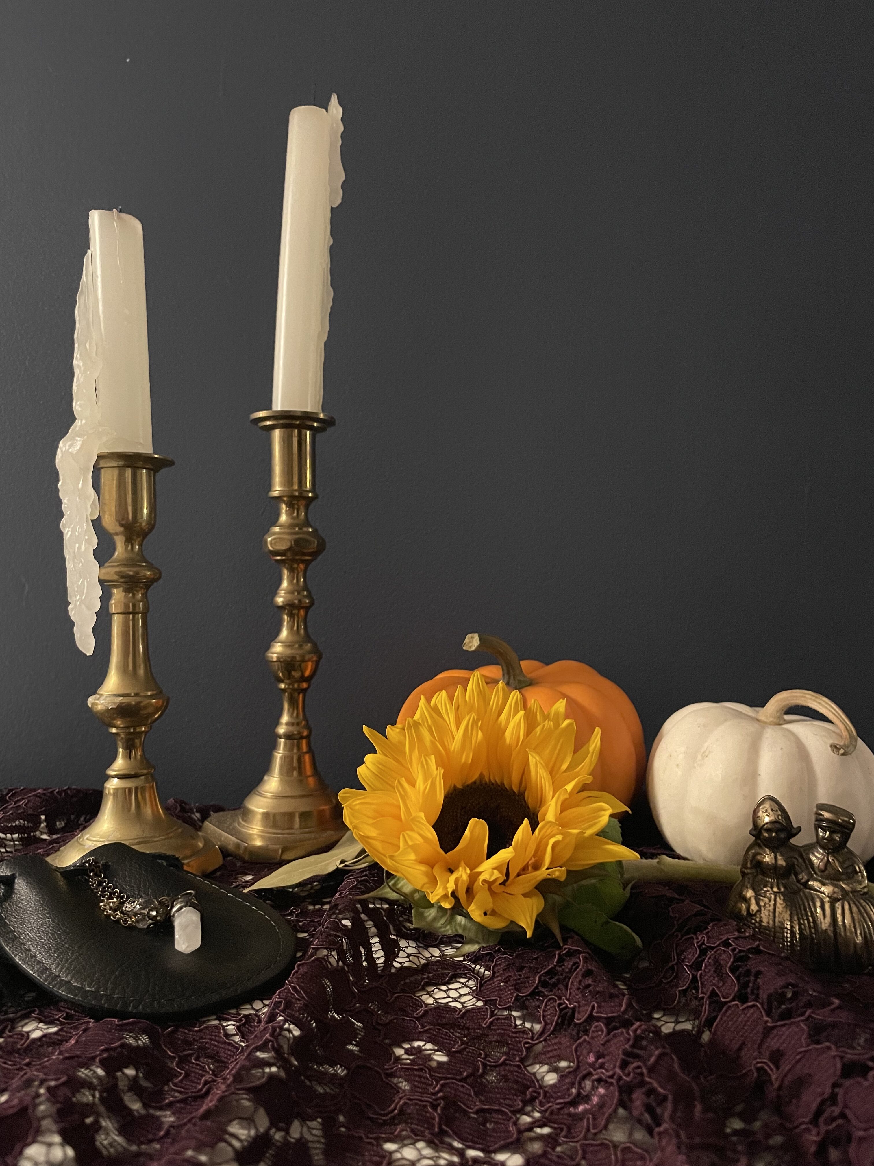 An altar honouring ancestors and harvest time. Includes candles, pumpkins, a sunflower, a witch bell, bay leaves for cleansing and pendulum for divination.